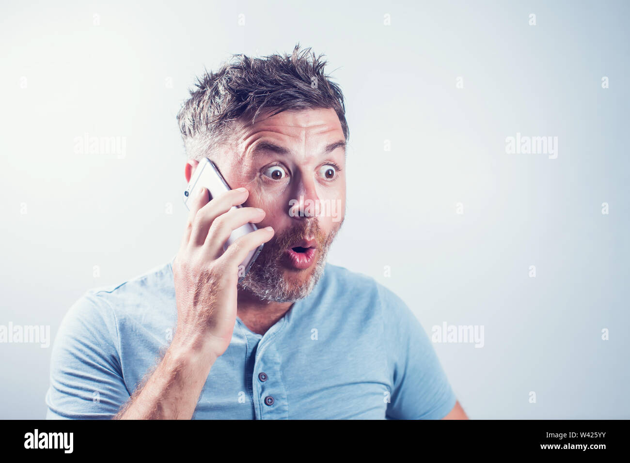 Handsome young man surprised using mobile phone Stock Photo