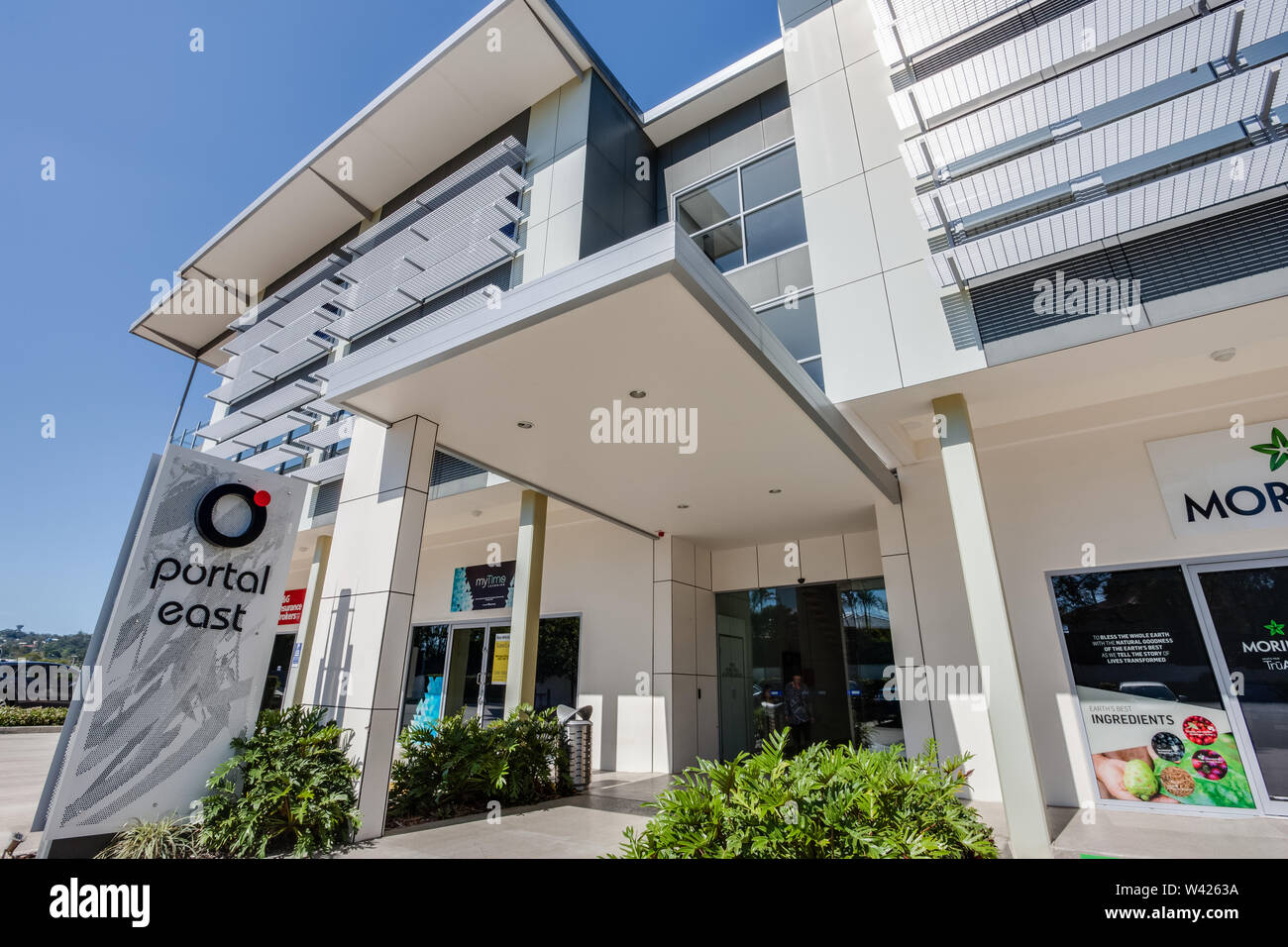 Stylish 4-storey building design with a covered entrance and a bolted logo of the company Portal East. Stock Photo