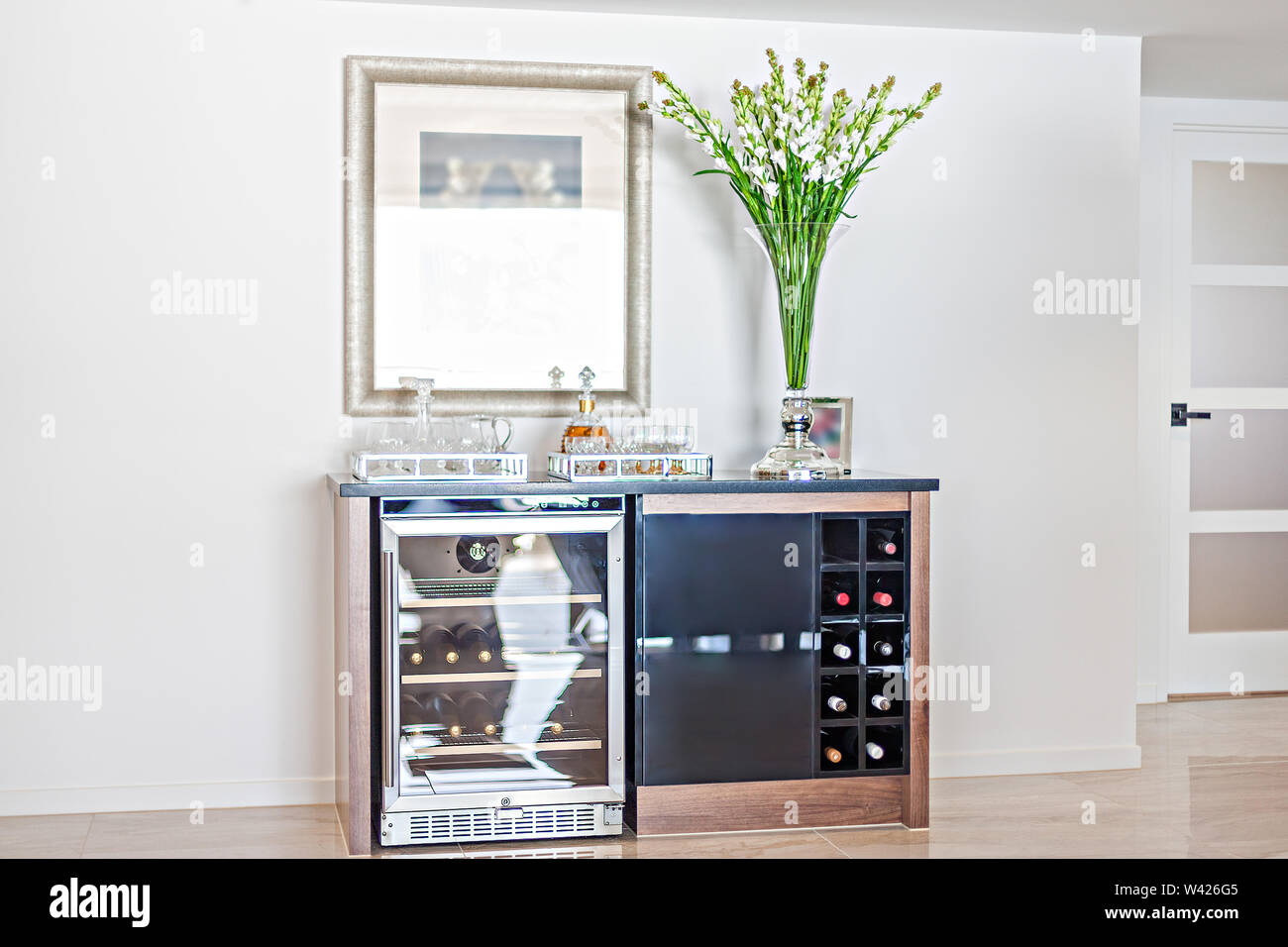 An aesthetic home bar with a beer chiller, a wine rack, and barware