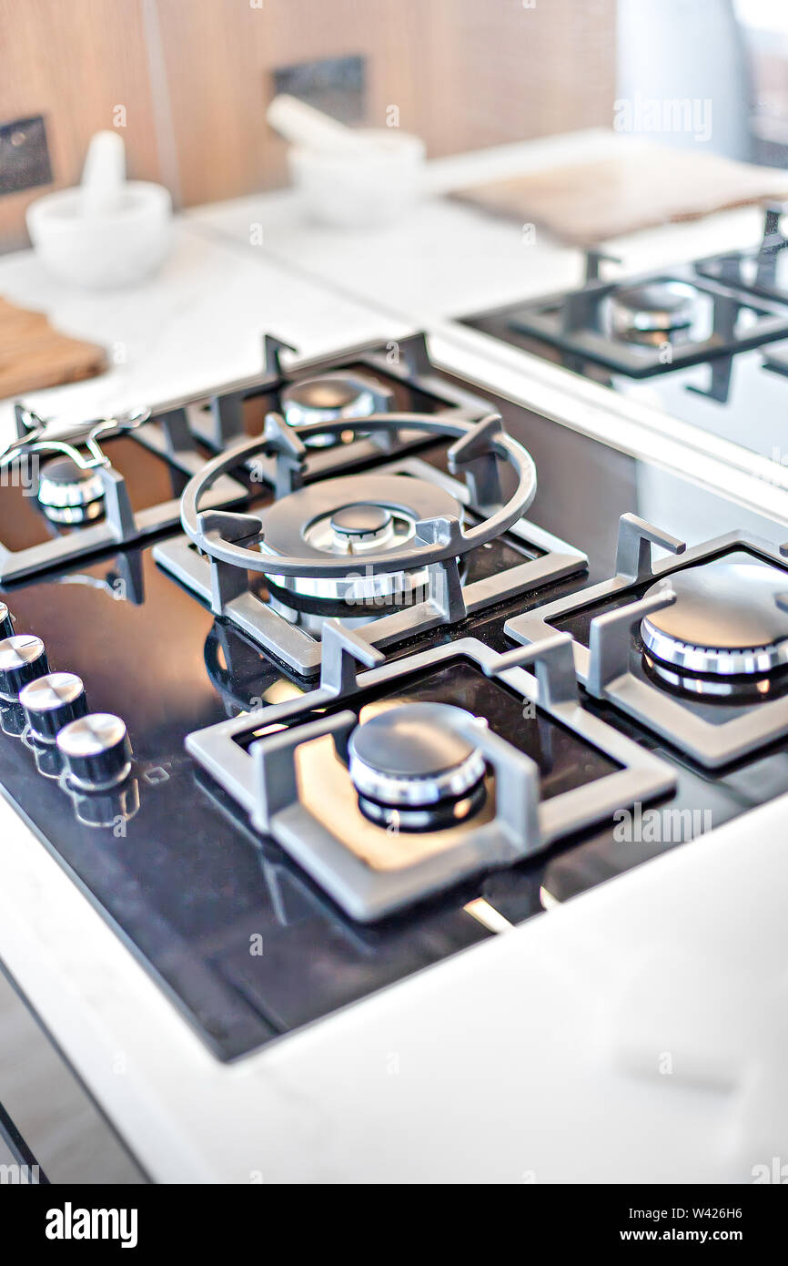 Stainless grey metal kitchen gas stove installed on a the kitchen with a  dark grey table top Stock Photo - Alamy