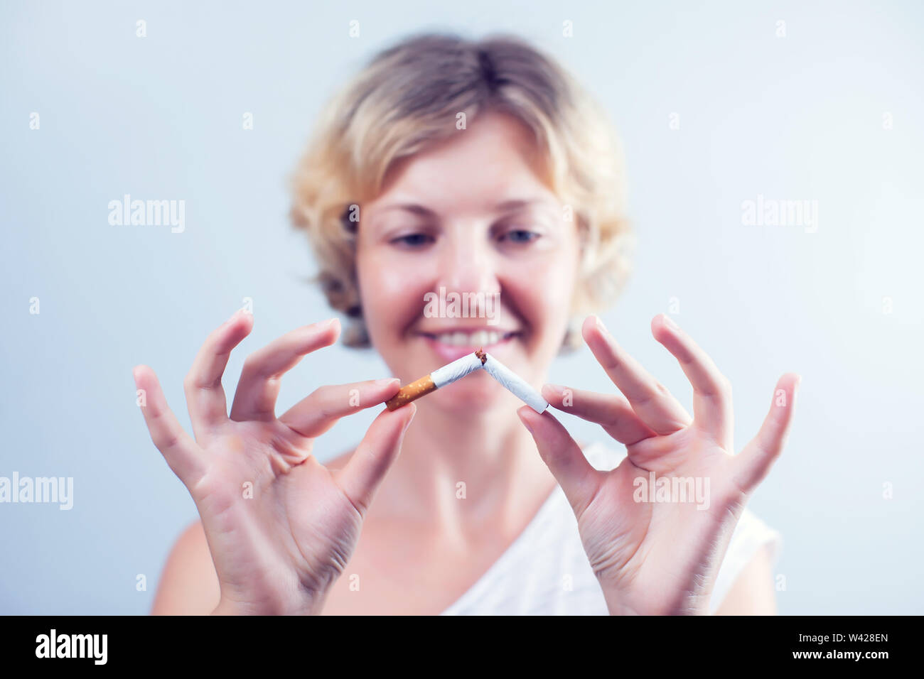 Quit Smoking. Closeup Of Beautiful Happy Female Breaking Cigarette. Portrait Of Smiling Woman Holding Broken Cigarette In Hands. Healthy Lifestyle Con Stock Photo