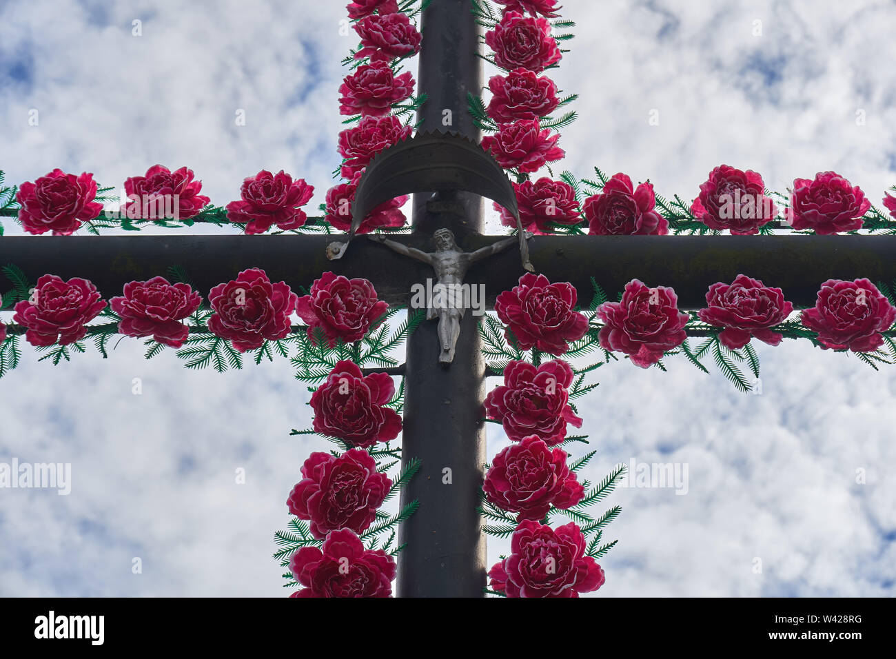 Traditional Catholic cachapel near the road in the shape of a cross with plastic artificial flowers, Biale, Poland Stock Photo