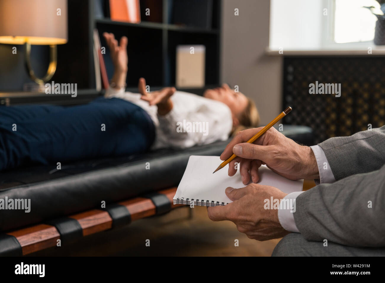 Male psychotherapists hands making notes in his notepad Stock Photo