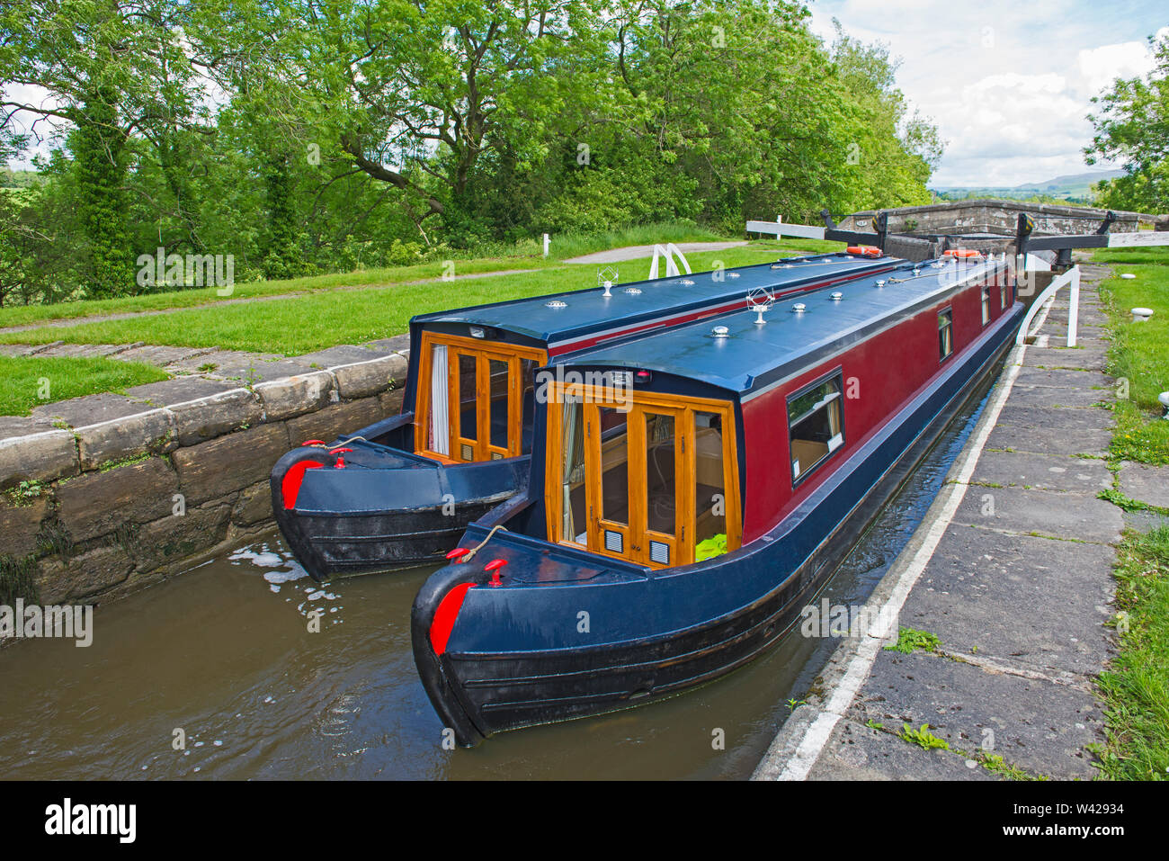 Two narrowboats traveling through a deep lock in English rural