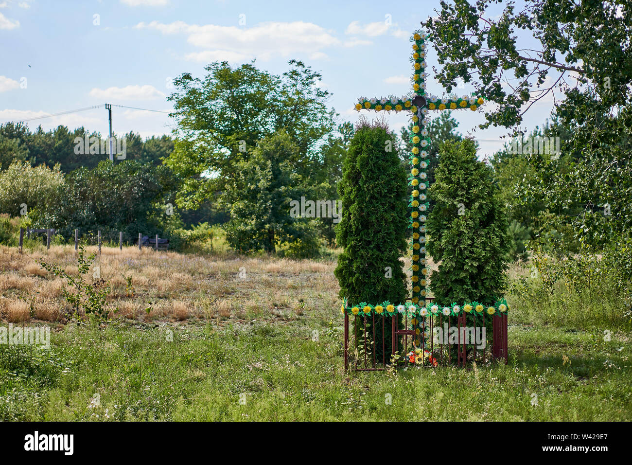 Traditional Catholic cachapel near the road in the shape of a cross with plastic artificial flowers, Biale, Poland Stock Photo