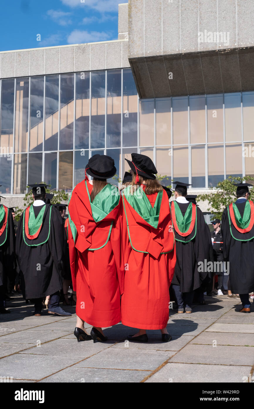 Higher education in the UK - successful PhD doctoral students at the graduation ceremony at Aberystwyth university, after receiving their degrees,  wearing their traditional tudor style bonnet caps and  red coloured  gowns. July 2019 Stock Photo