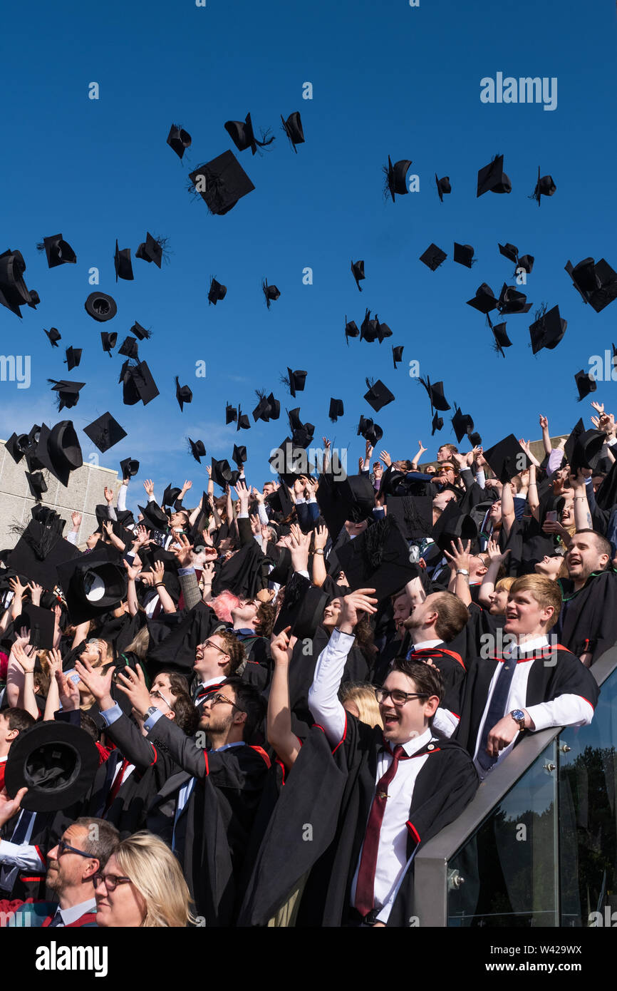 Higher education in the UK - successful students at the graduation ceremony at Aberystwyth university, after receiving their degrees,  throwing their mortar board caps in the air in celebration . July 2019 Stock Photo