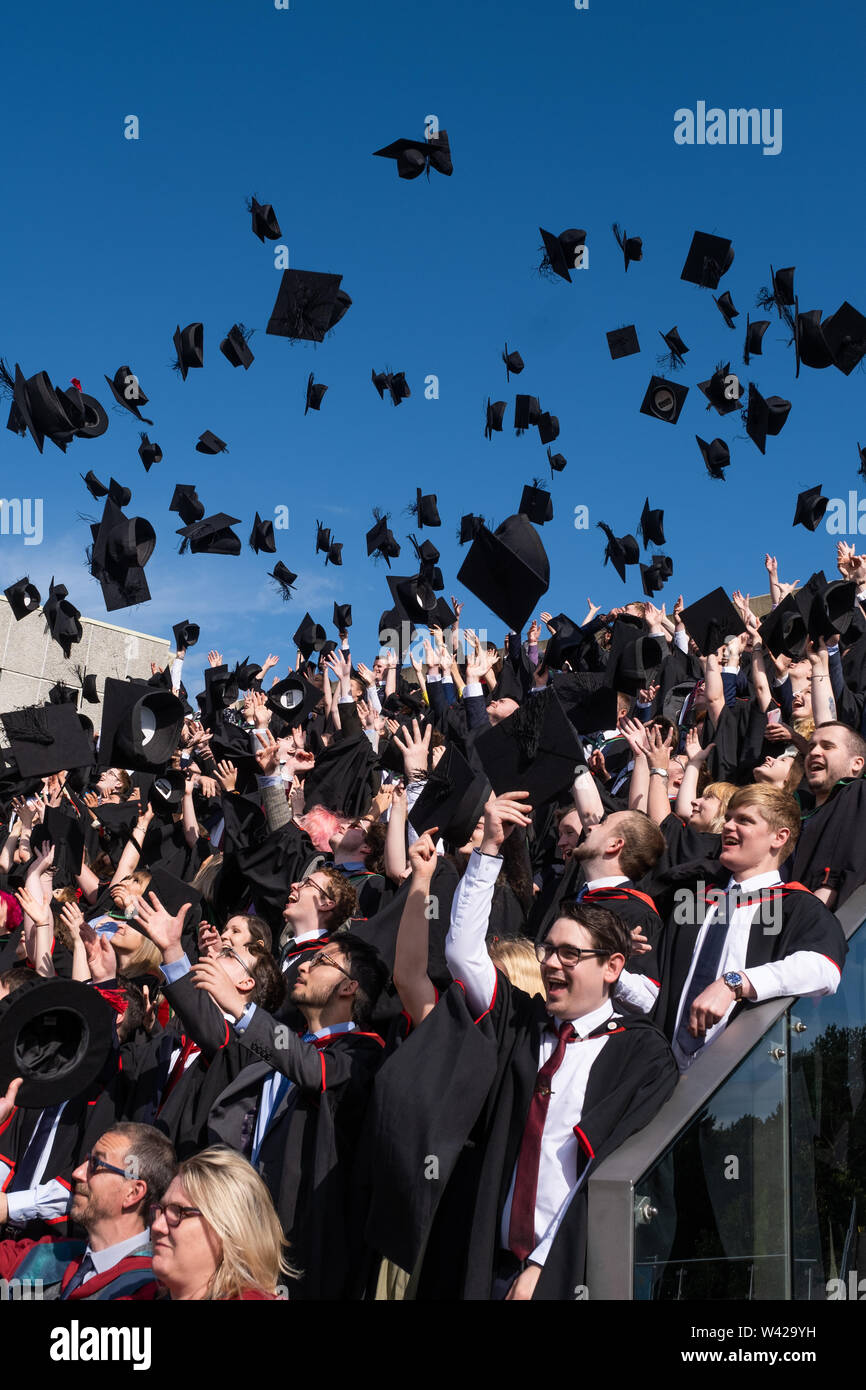 Higher education in the UK - successful students at the graduation ceremony at Aberystwyth university, after receiving their degrees,  throwing their mortar board caps in the air in celebration . July 2019 Stock Photo