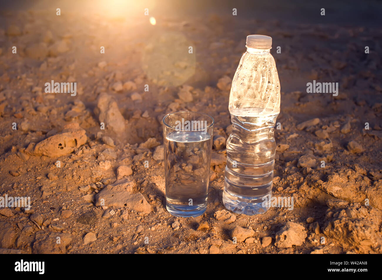 https://c8.alamy.com/comp/W42AN8/glass-and-bottle-of-water-on-sand-in-the-desert-thirsty-heat-and-drought-concept-W42AN8.jpg