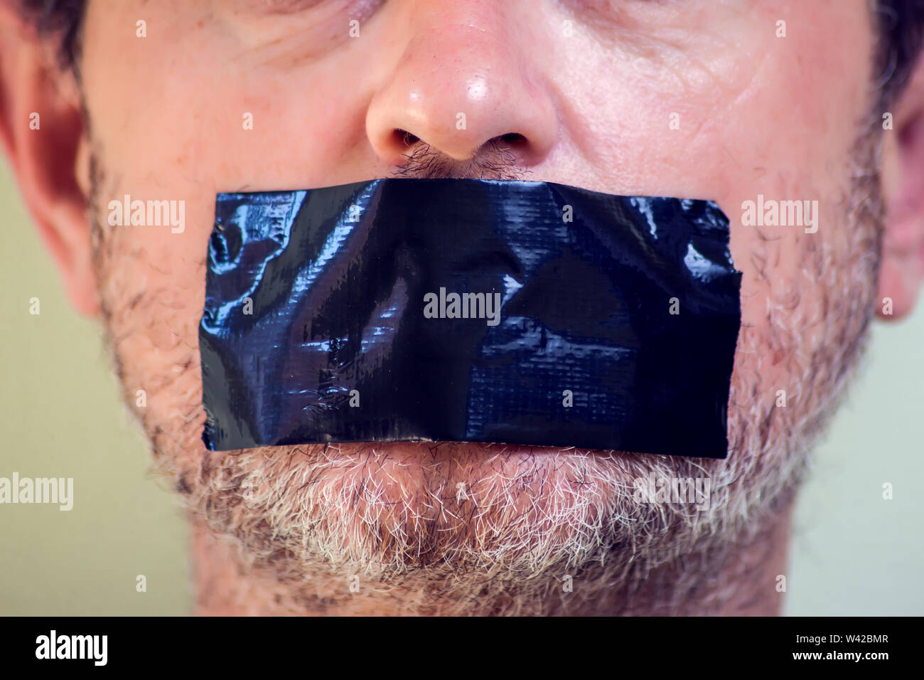 Upset man with self-adhesive tape over her mouth. Stock Photo