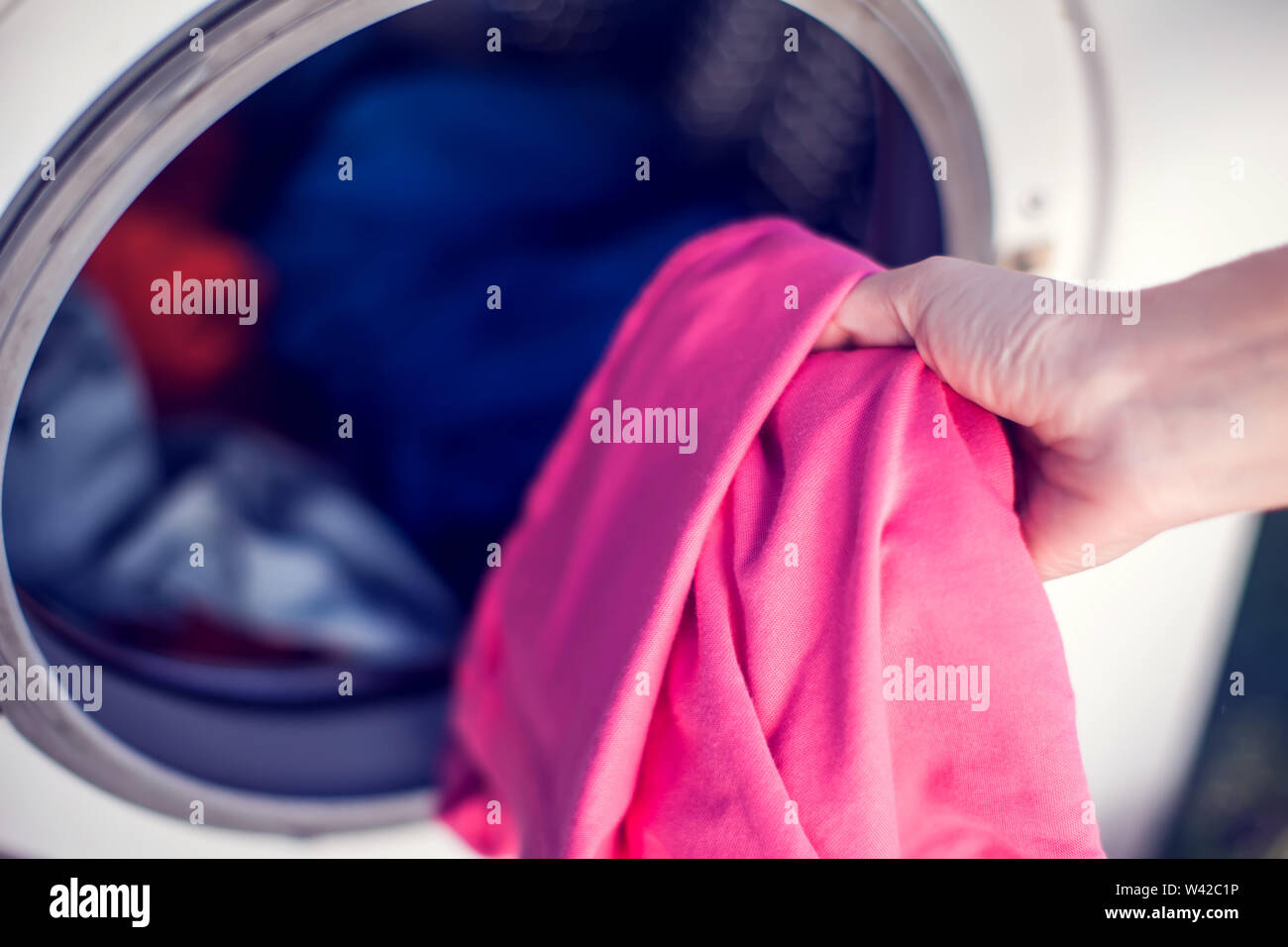 Closeup Of Person Hand Putting Dirty Clothes In Washing Machine For