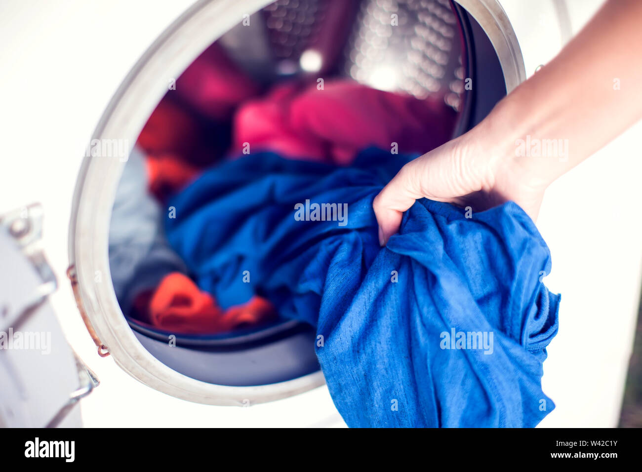 Closeup Of Person Hand Putting Dirty Clothes In Washing Machine For