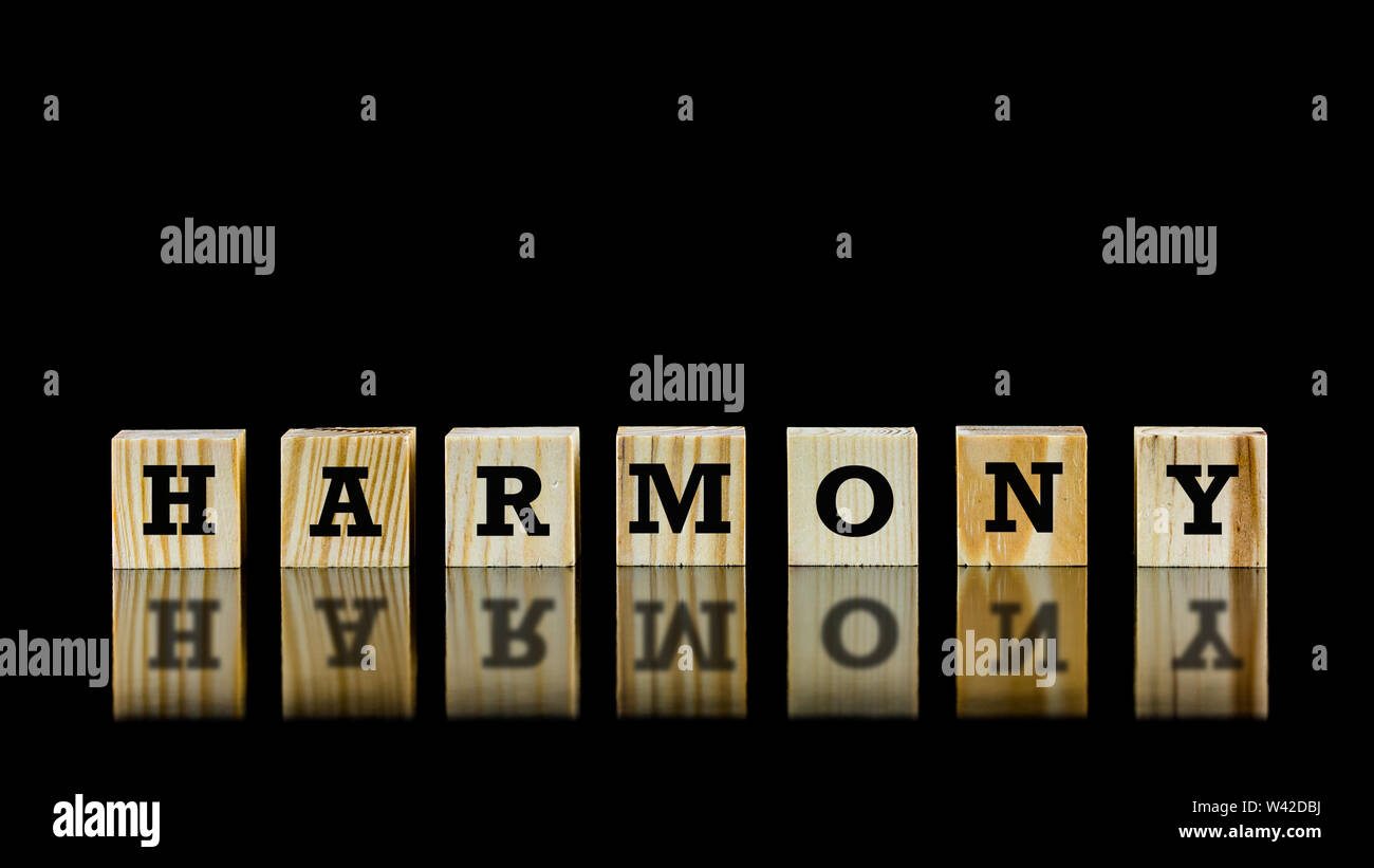 The word - Harmony - on wooden cubes beautifully reflected on a dark surface below against a black background with copyspace. Stock Photo