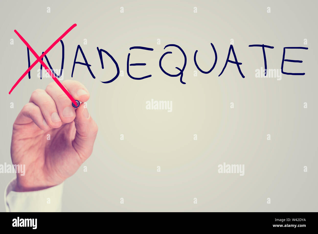 Concept of Inadequate versus Adequate with a business man crossing through the In in the word Inadequate with a red pen on a virtual screen with blank Stock Photo
