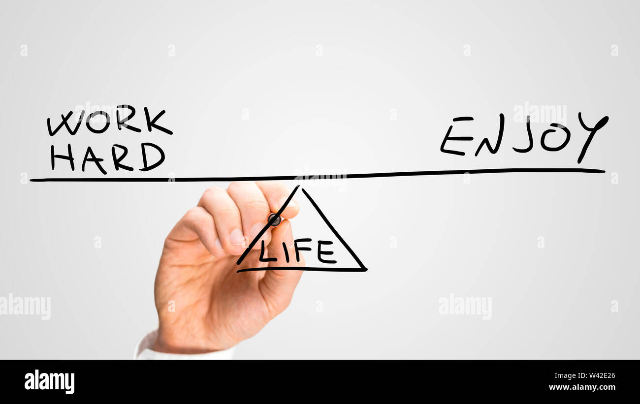 Conceptual image of balancing Work and Enjoyment in life with a man drawing a seesaw on a virtual screen in equilibrium with the handwritten text - Wo Stock Photo
