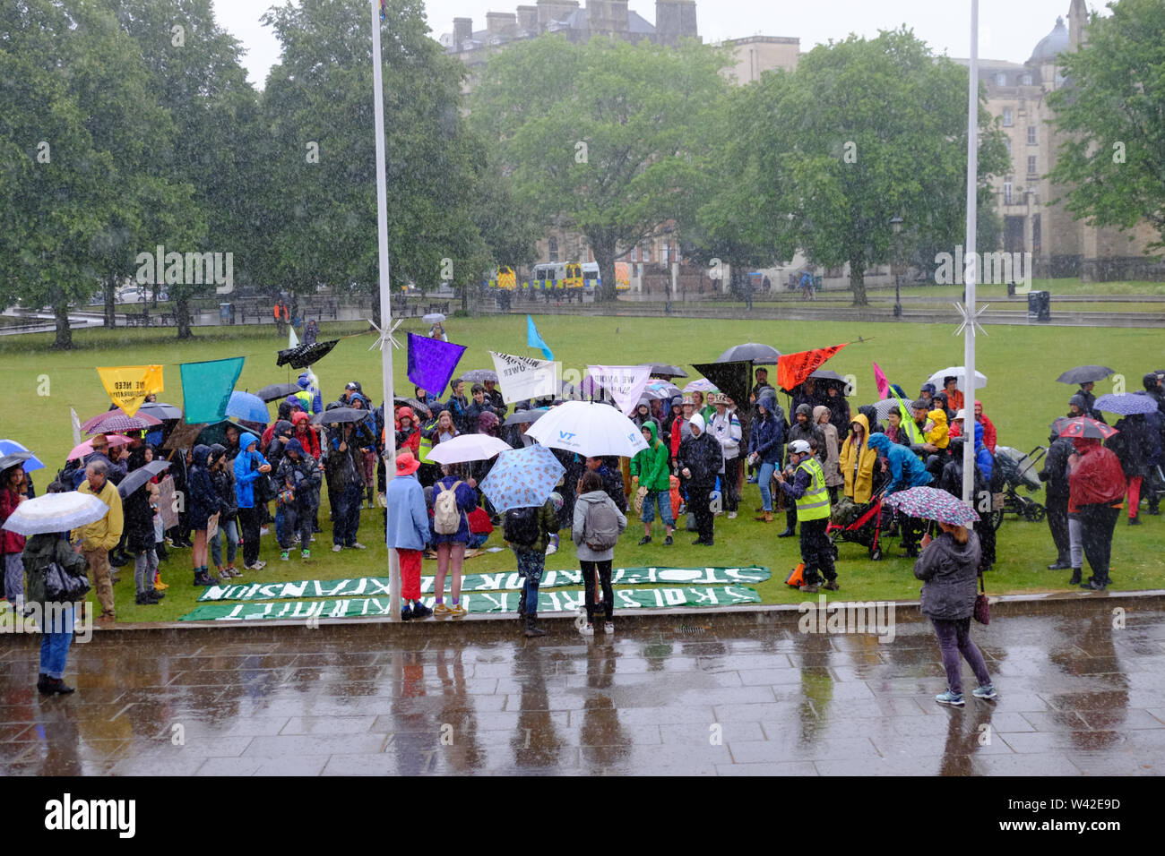 Bristol, UK. 19th July 2019. Rain pours on the Extinction Rebellion youth rally on college Green in Bristol City center. This is the 5th day of the climate change protest in the city. Credit: Mr Standfast/Alamy Live News Stock Photo