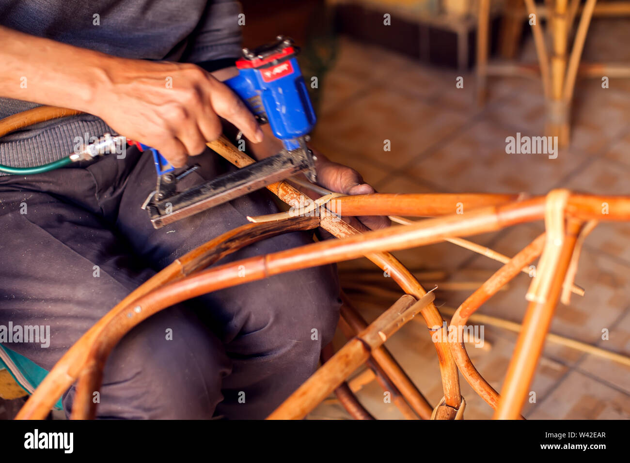 Man in process of manufacturing furniture rattan chair and table Stock