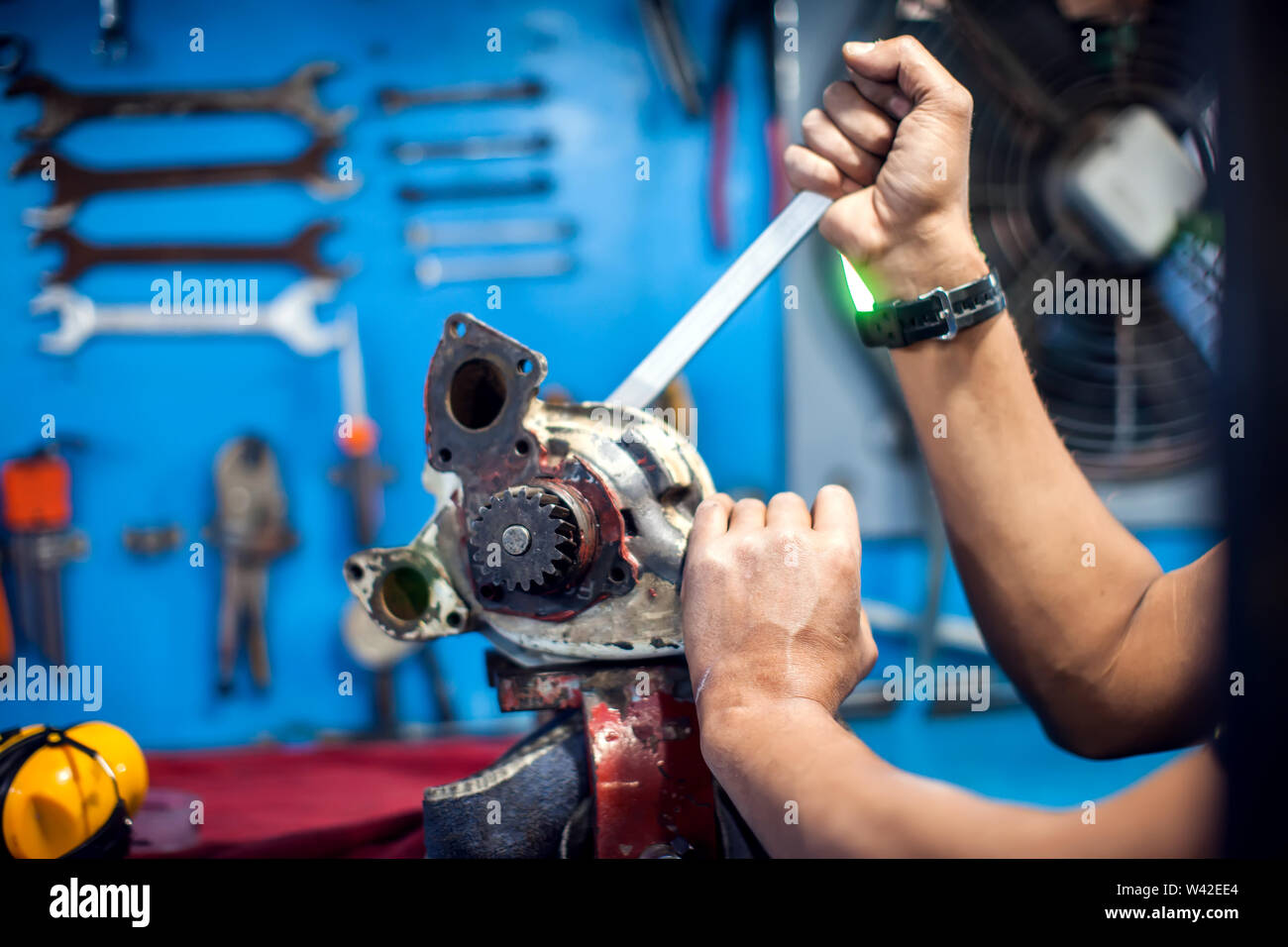 Man repairs part of engine with wrench. People, work concept Stock