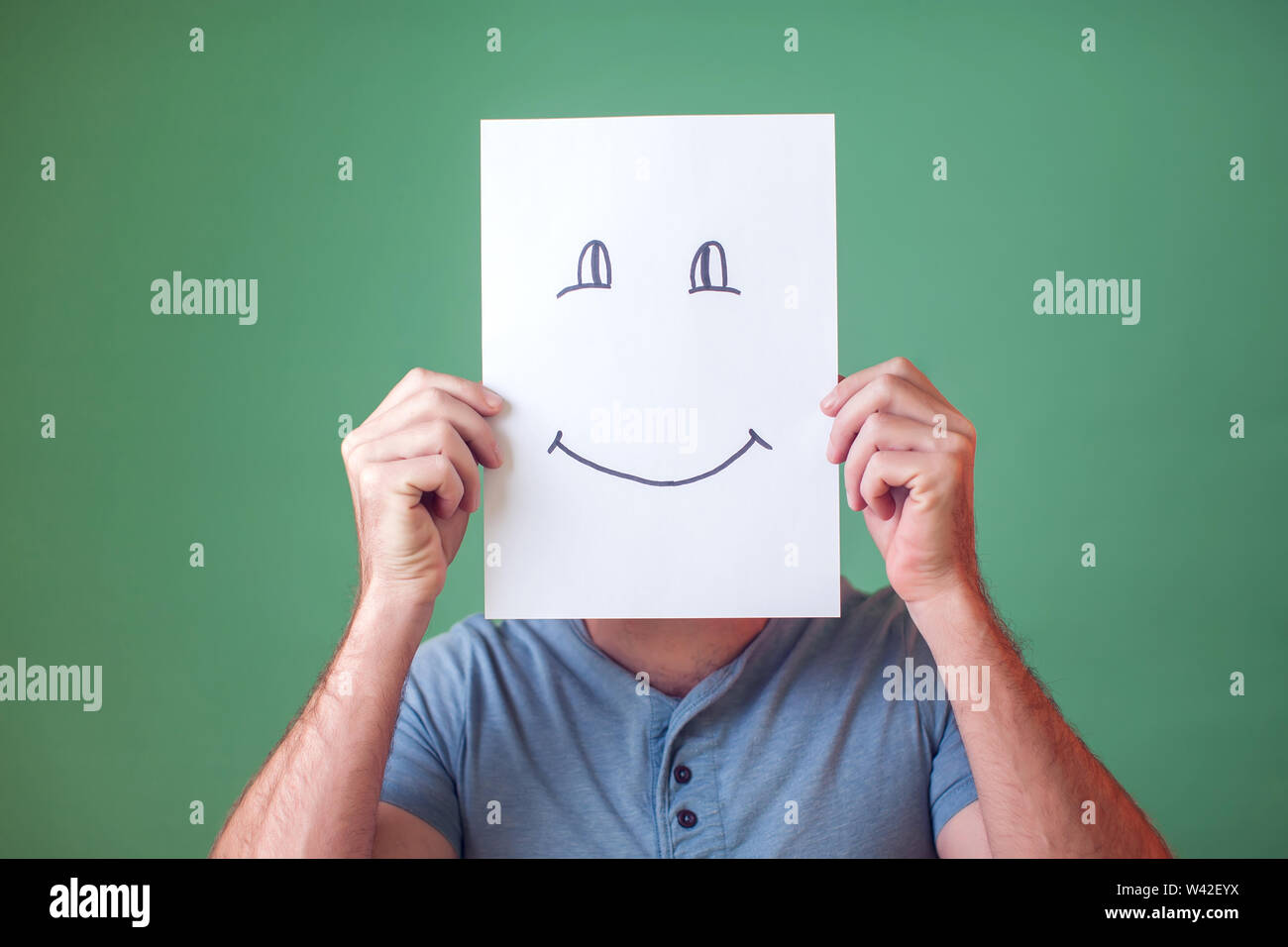 A portrait of man holding a card with smiling face. People, emotions and lifestyle Stock Photo