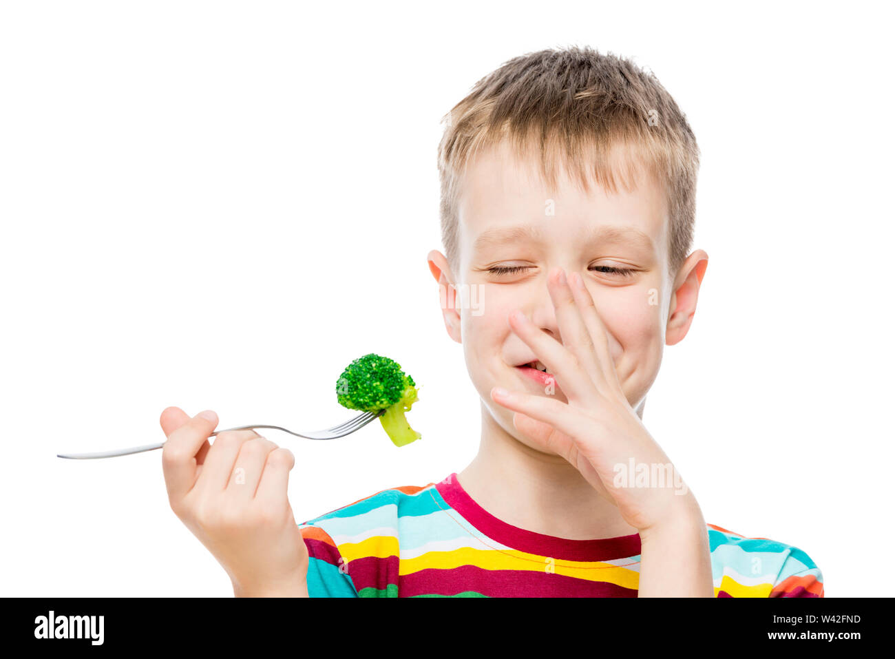 The boy with contempt looks at broccoli, portrait is isolated on white background Stock Photo