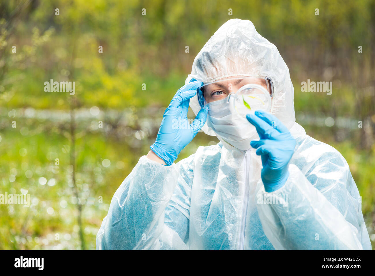 chemist researcher in protective clothing examines infected plants from a forest lake Stock Photo