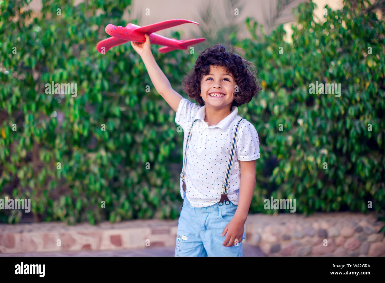 Young happy boy playing with red airplane outdoor. Children and ...