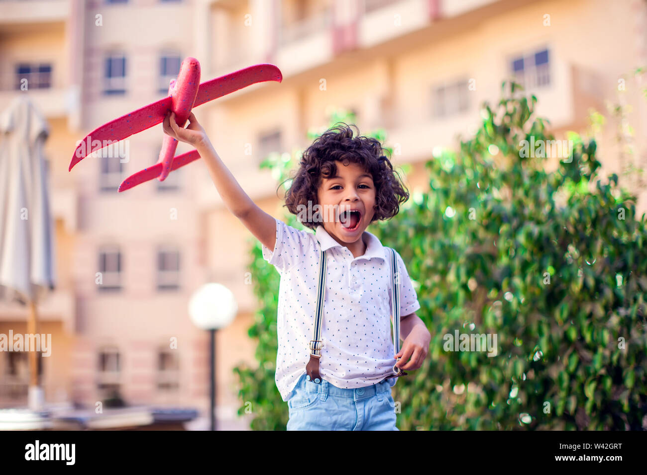 Young happy boy playing with red airplane outdoor. Children and ...