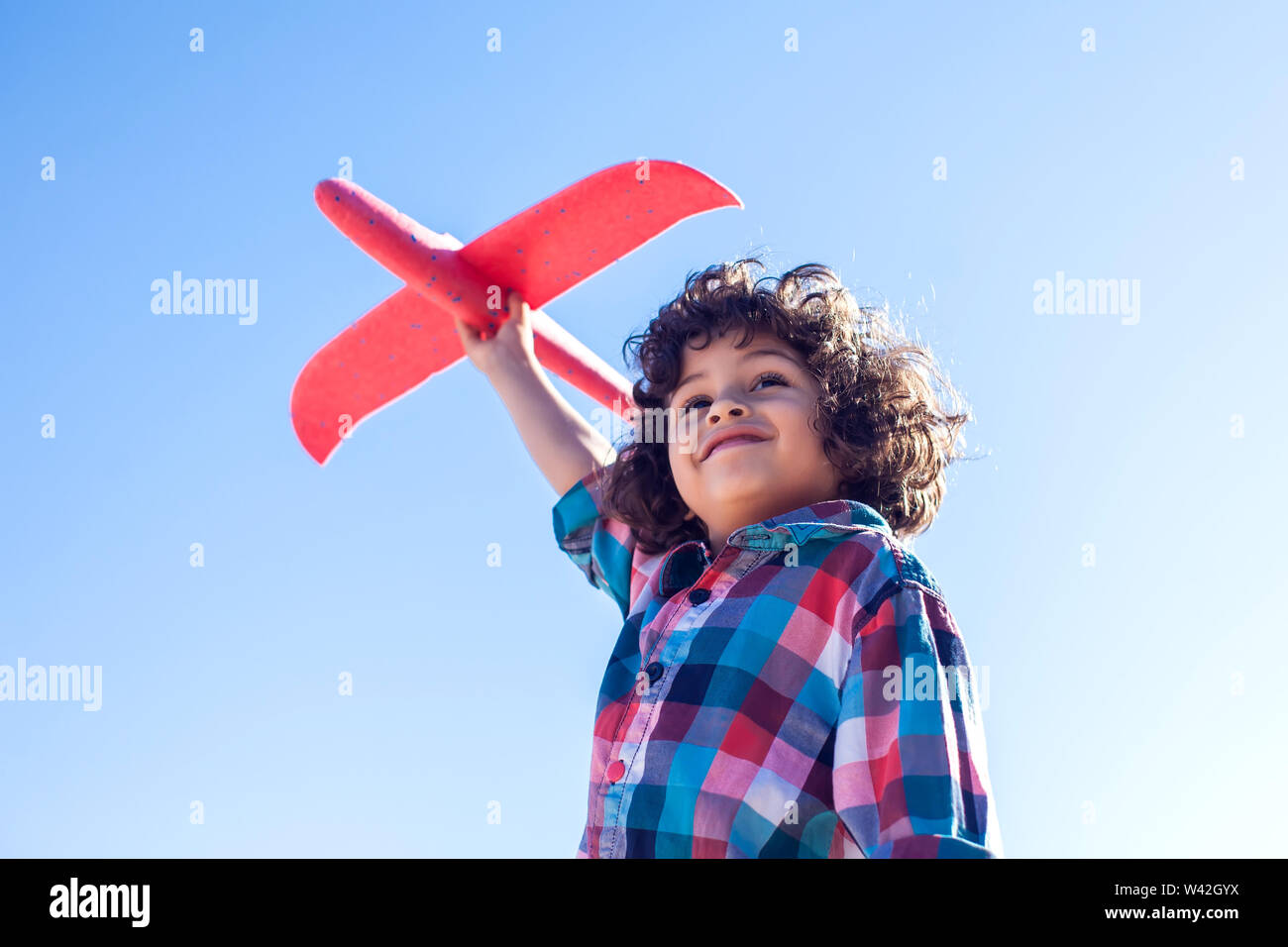 Young happy boy playing with red airplane outdoor. Children and ...