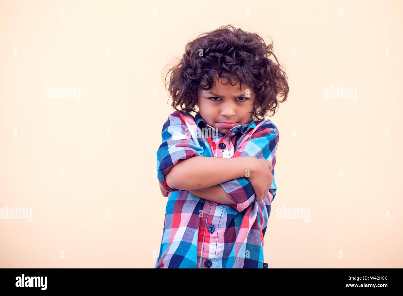 Sad kid with curly hair cry over isolated background Stock Photo