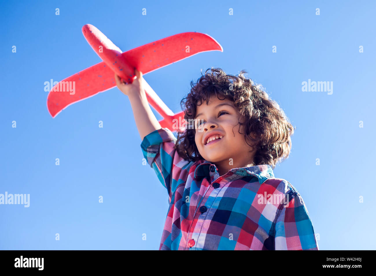 Young happy boy playing with red airplane outdoor. Children and ...