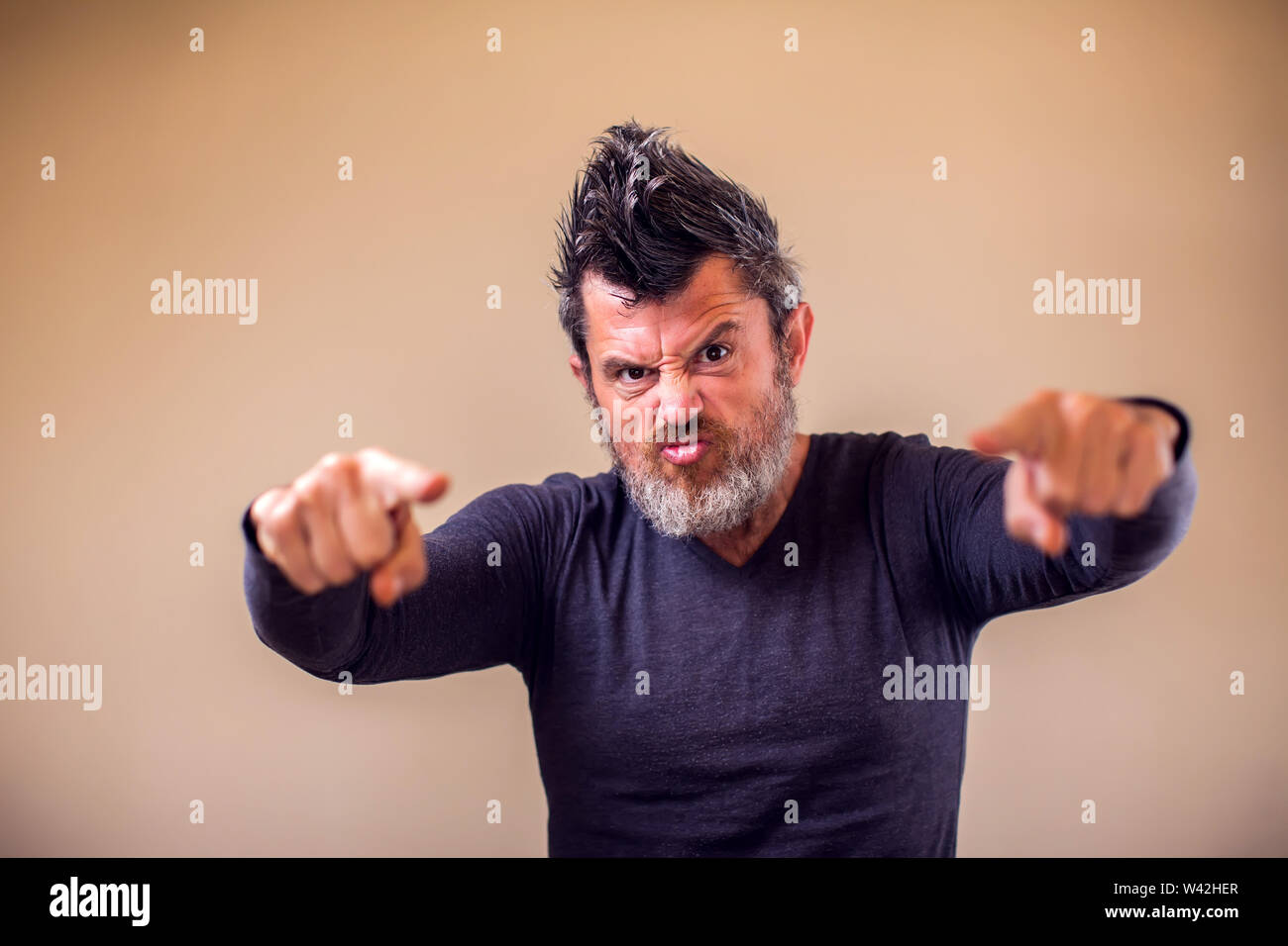 Closeup portrait of an angry adult man with a beard and iroquois poins with fingers at camera. People and emotions concept Stock Photo