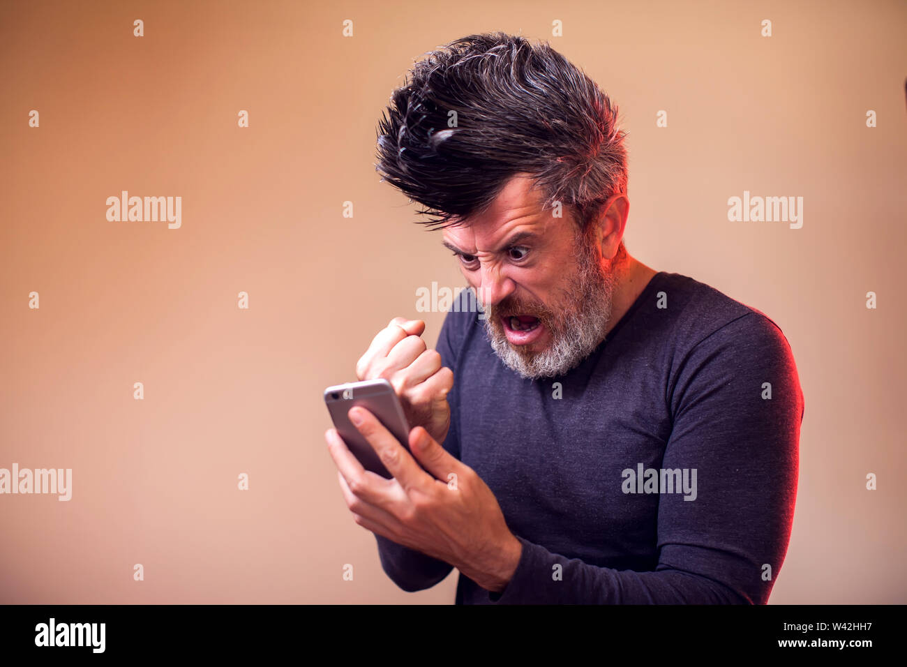 Premium Photo Handsome bearded guy holds smartphone and plays online games joyful man wearing a black stylish hat and a blue shirt crazy emotions