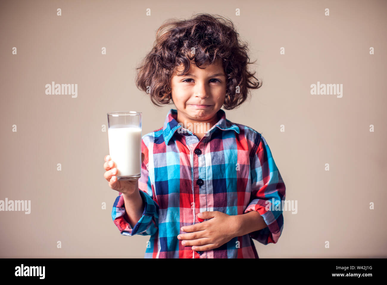 Kid boy with stomach pain holding a glass of milk. Dairy Intolerant