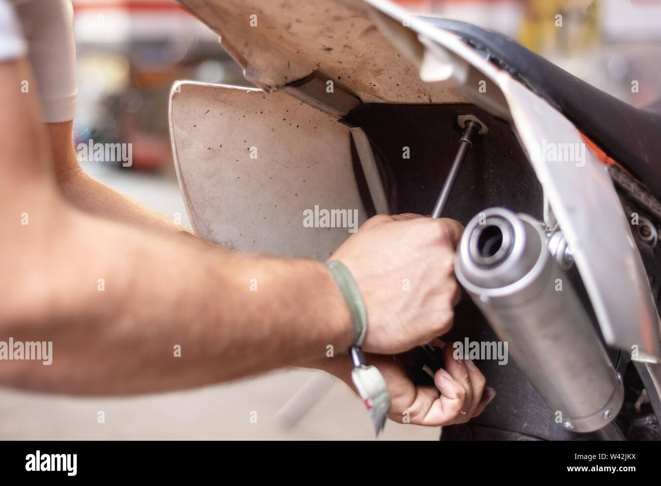 Motorbike mechanic repairing an exhaust pipe system at garage Stock