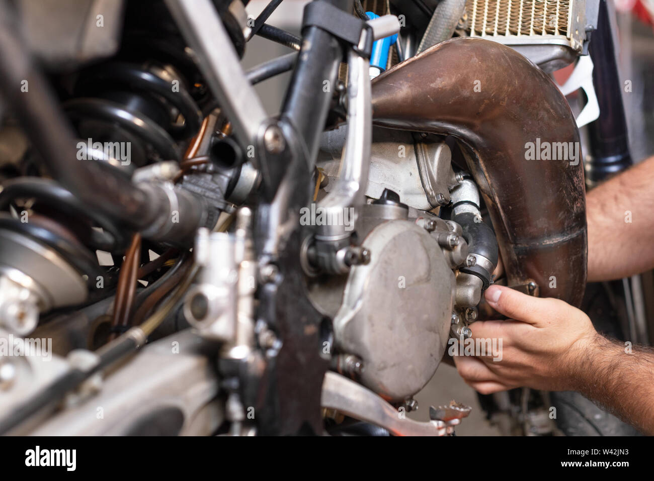 Motorbike mechanic repairing an exhaust pipe system at garage Stock