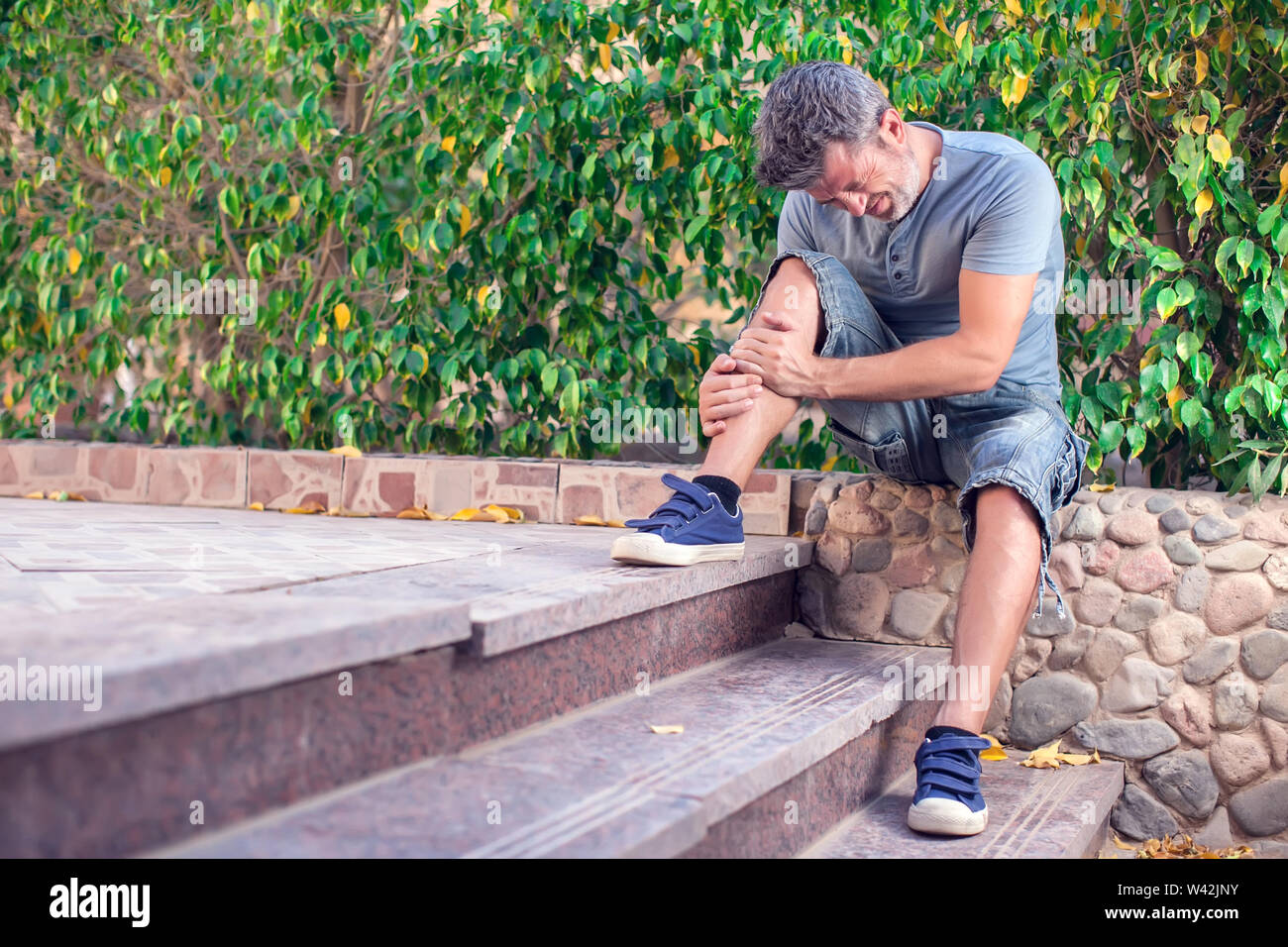 Man feels strong foot pain while walking outdoor. People, healthcare
