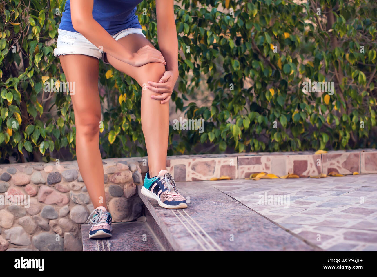 Woman feels knee pain while doing exercises. People, sport, healthcare and medicine concept Stock Photo