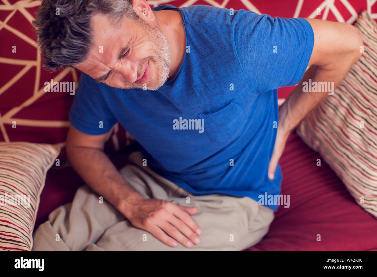 Man feels strong back pain at home. People, healthcare and medicine concept Stock Photo