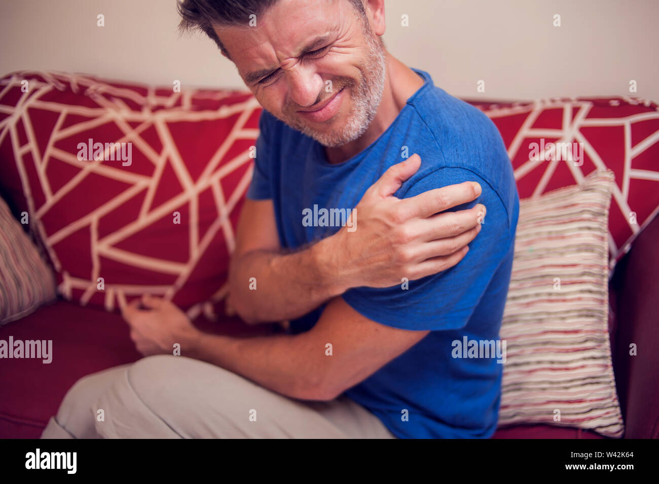 Man feels strong pain in shoulders at home. People, healthcare and medicine concept Stock Photo