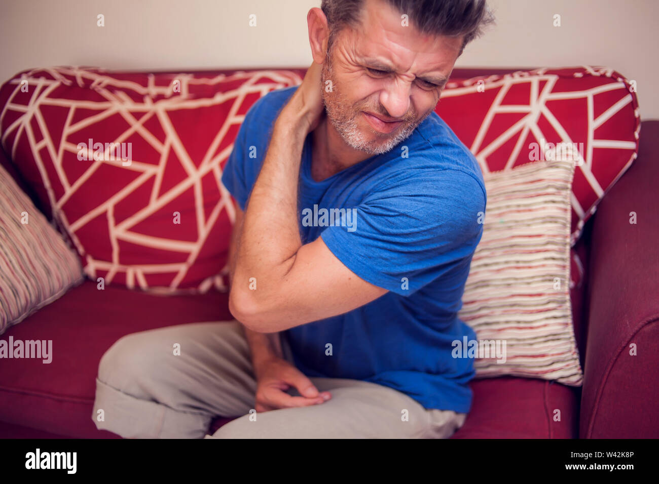 Man feels strong neck pain at home. People, healthcare and medicine concept Stock Photo