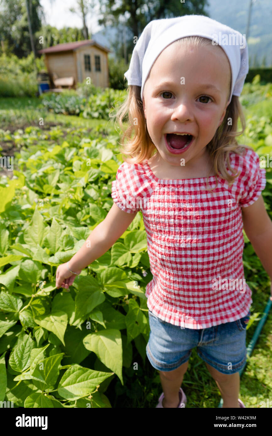 excited young girl points to the fast growing beans in her vegetable patch and smiles Stock Photo