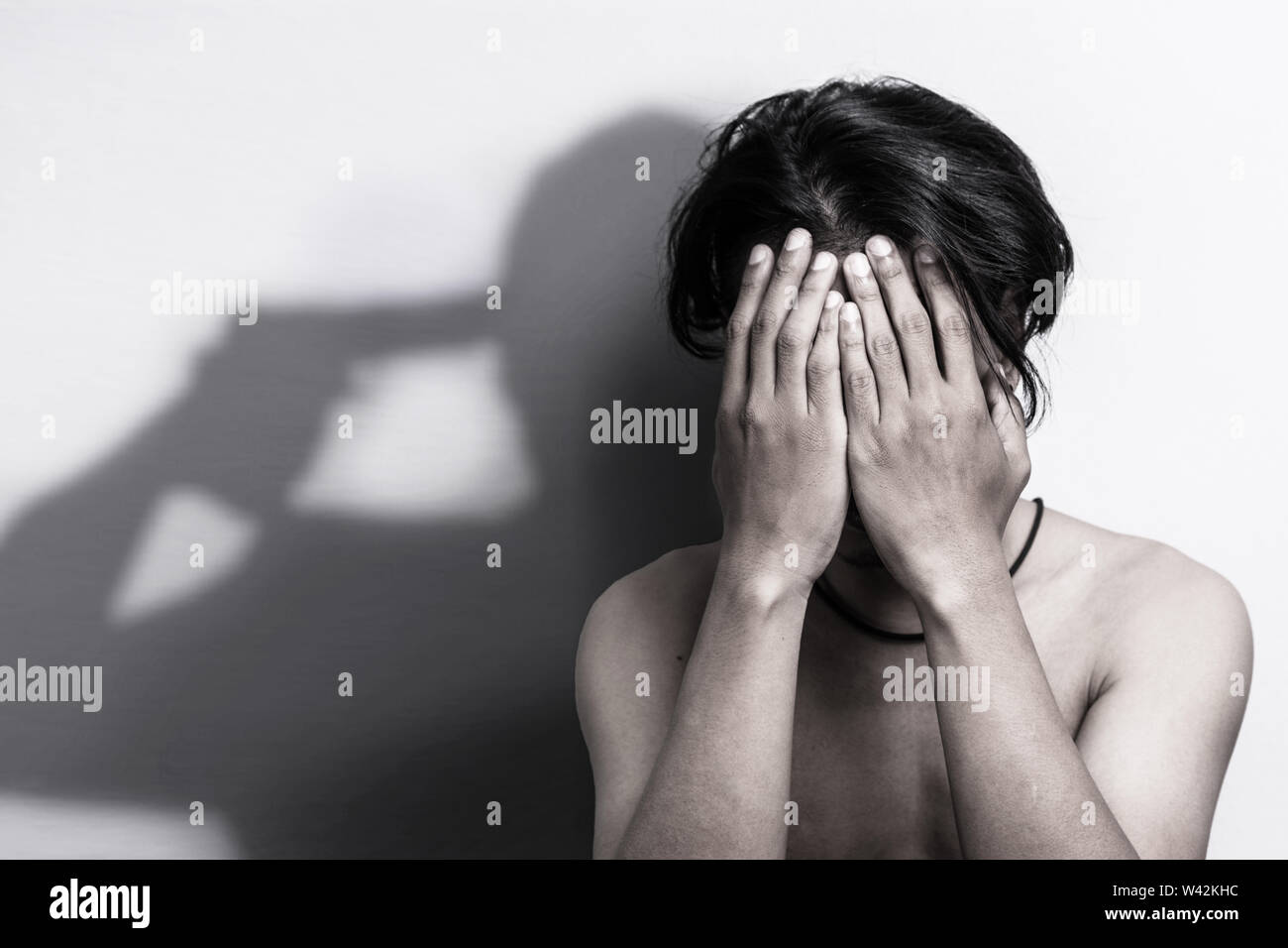 man with depression sitting head in hands with shadow of gun that was pointing his head, thinking to commit suicide. depression anxiety and bully vict Stock Photo
