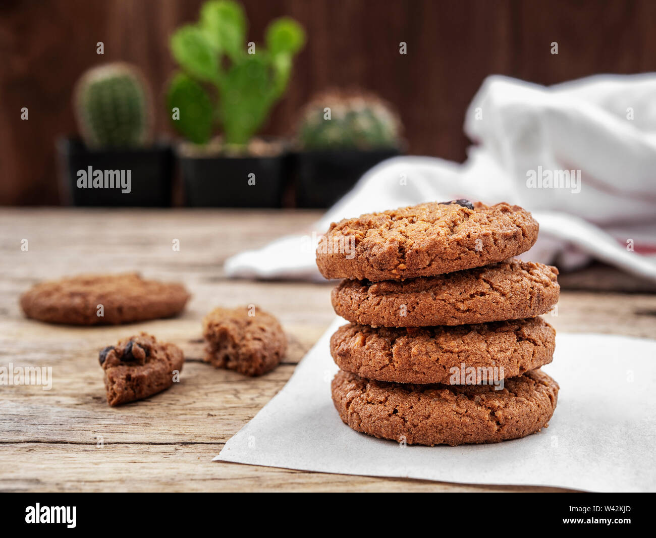stack of chocolate chip cookies on white napkin paper on wooden table decorate with cactus at background Stock Photo