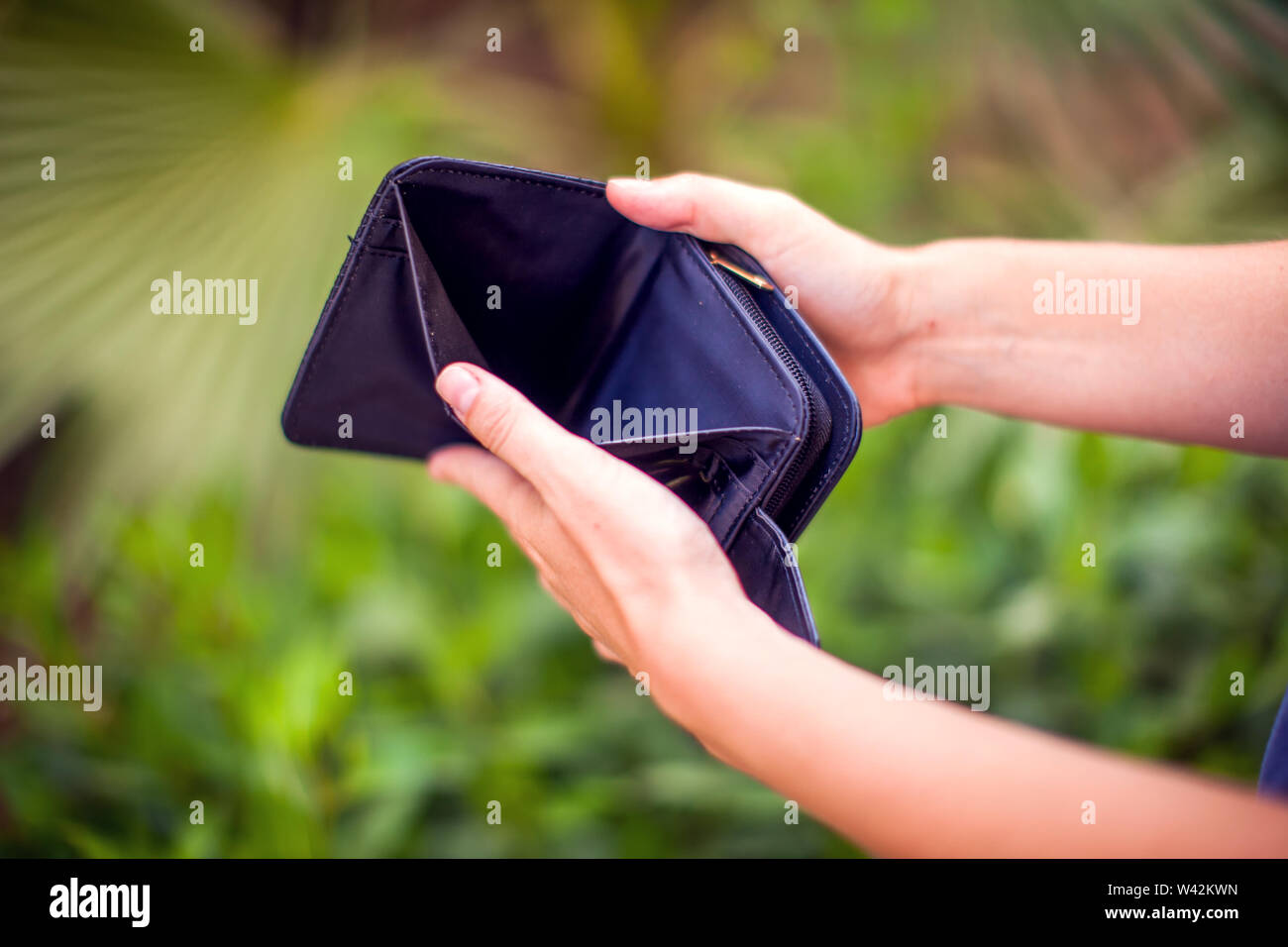 Woman holds an empty wallet in hands outdoor. Finance problem concept ...