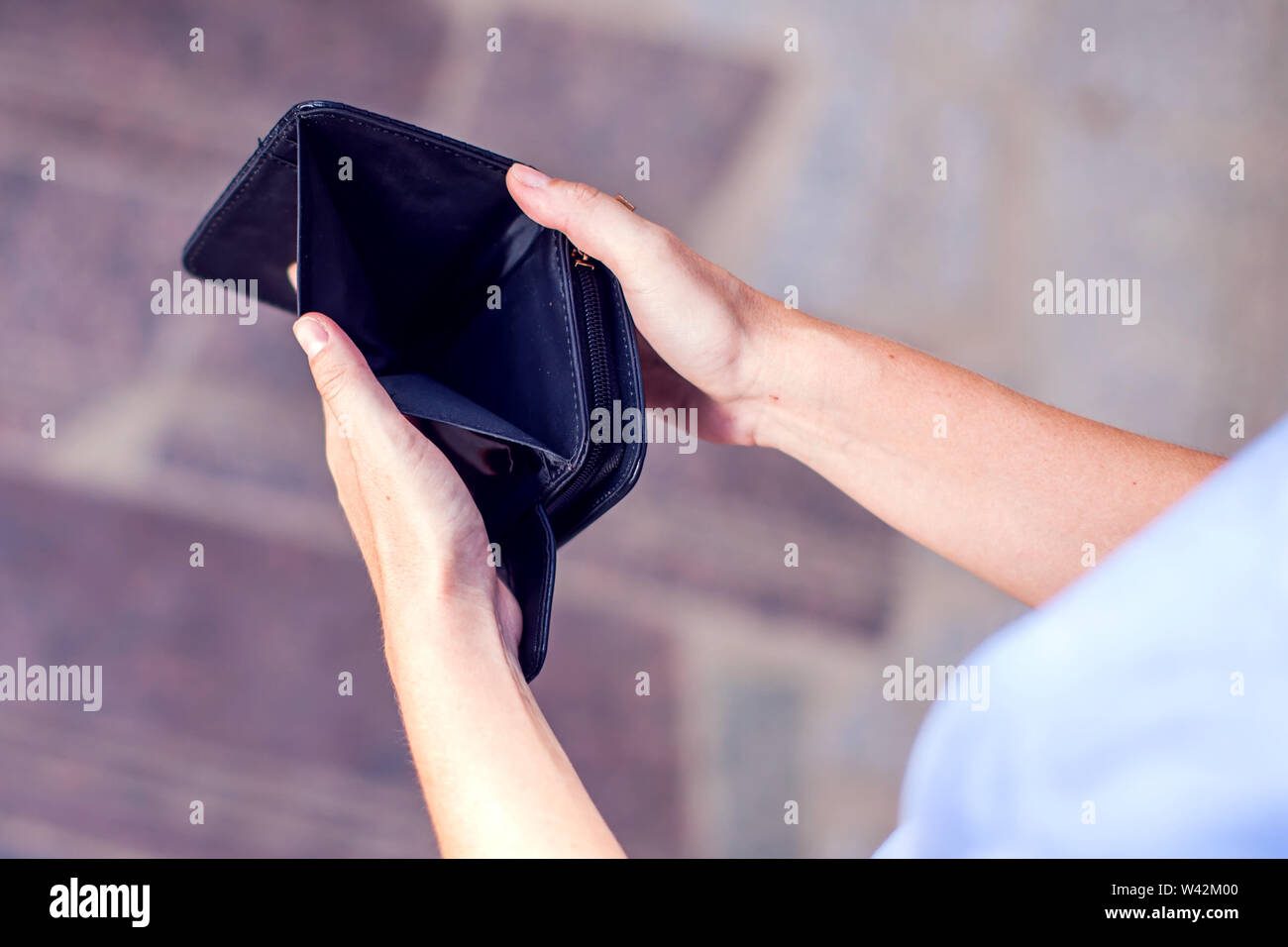 Woman holds an empty wallet in hands outdoor. Finance problem concept ...