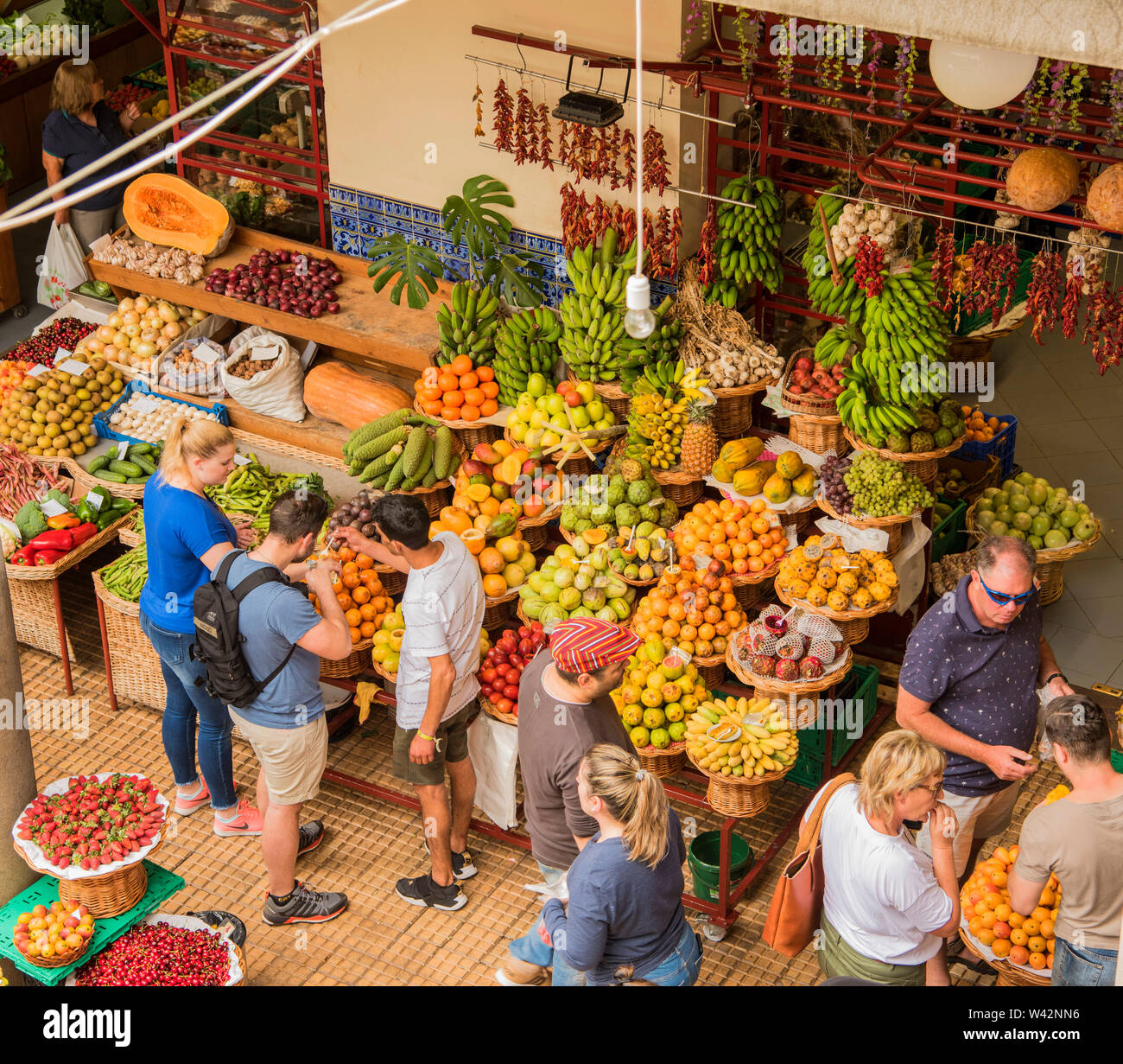 People buying fruit and vegetables from an outdoor market in Funchal