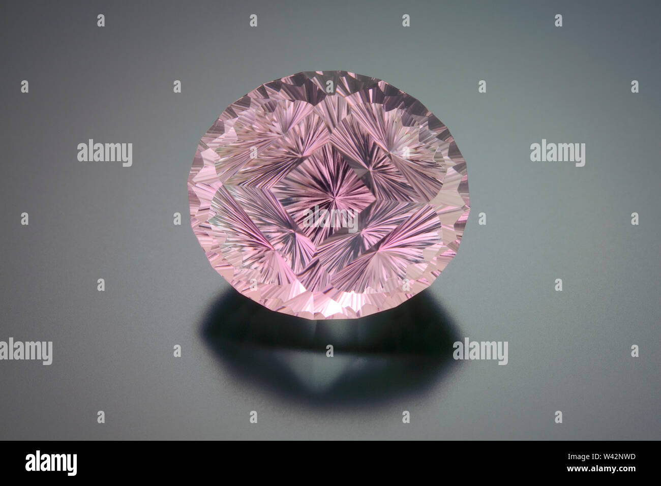 This large rose colored tourmaline fantasy cut gemstone site on a grey reflective background. Stock Photo