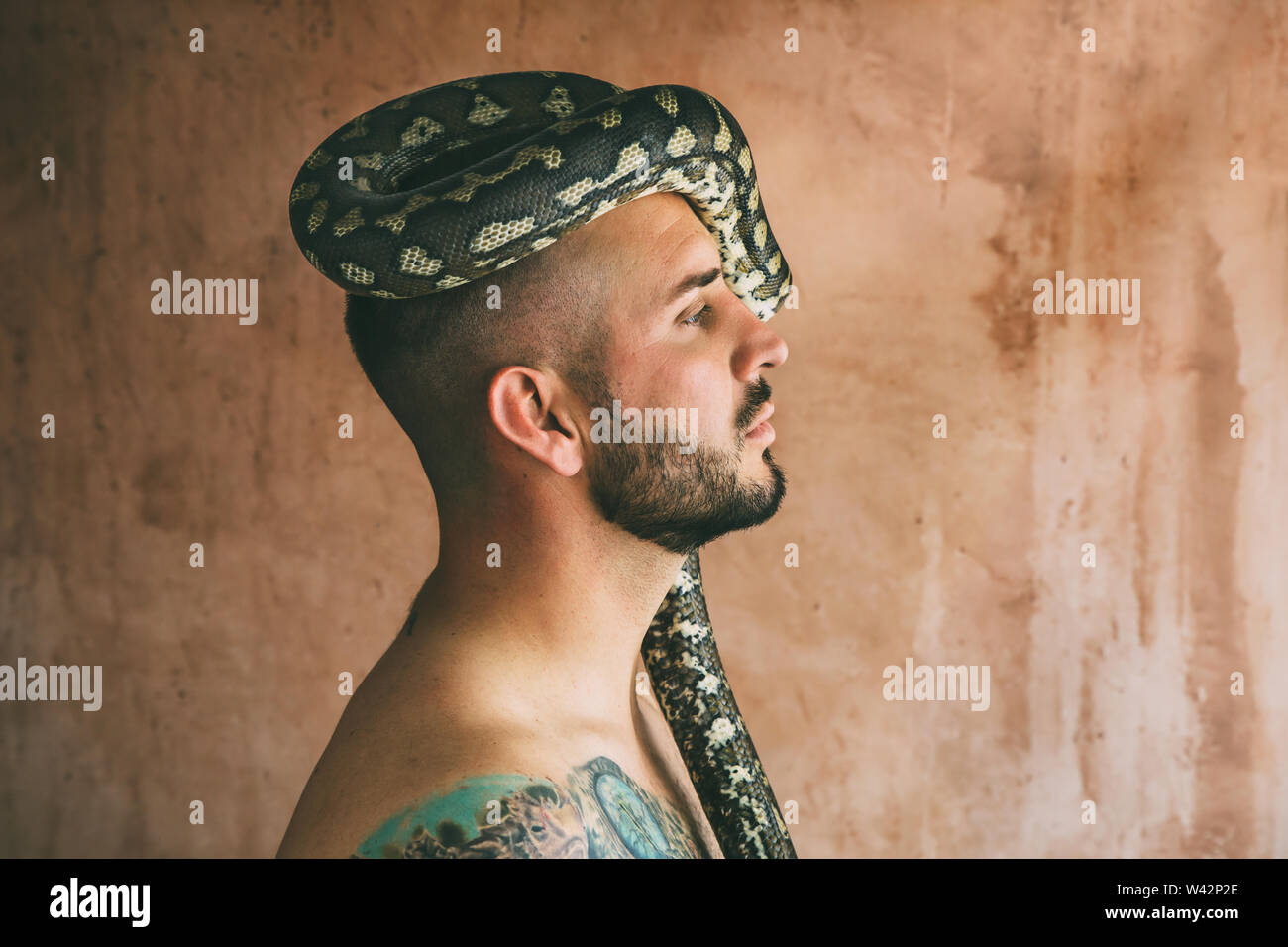 man posing with snake on his head Stock Photo