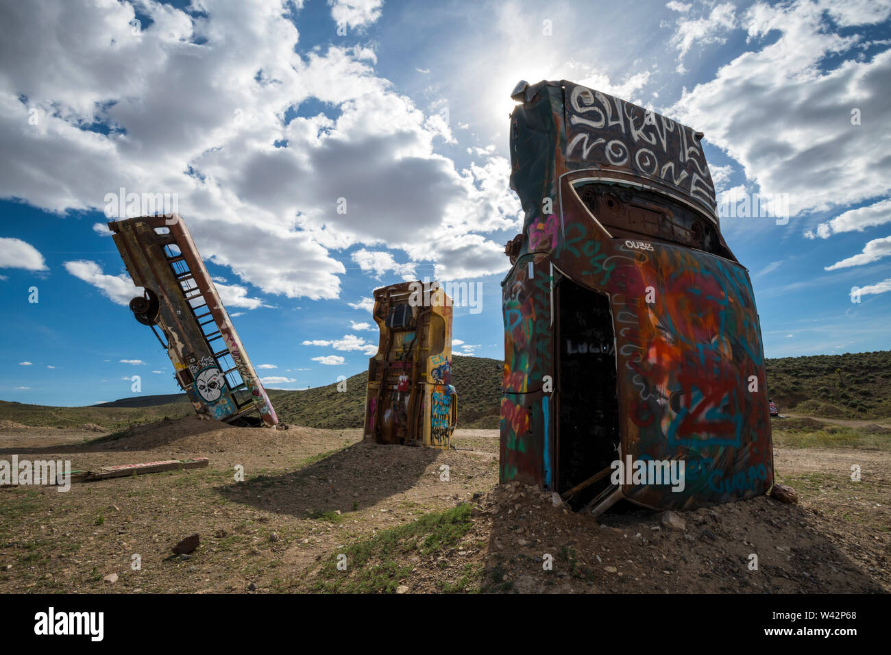 Two cars and a bus stand upright in the desert at the International Car