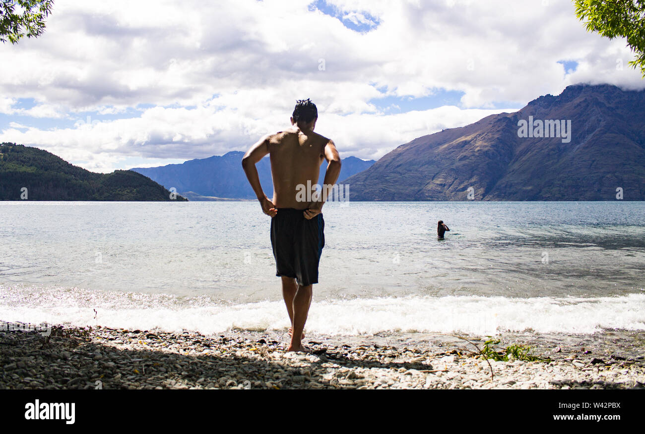 Teenage boy about to swim at the lake in Queenstown, New Zealand Stock Photo